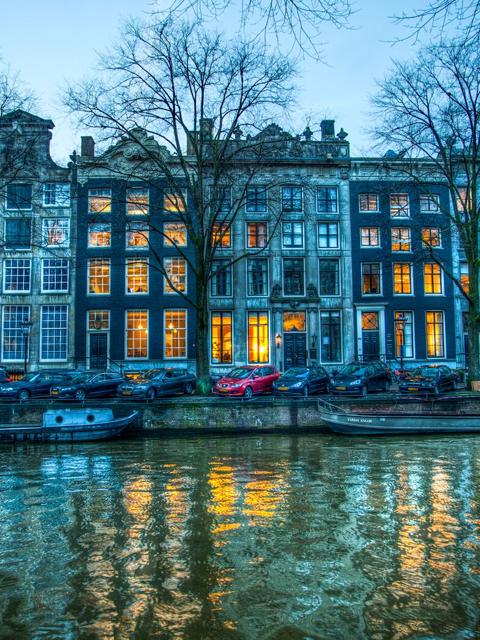 Canal houses reflected in the water at blue hour, Amsterdam